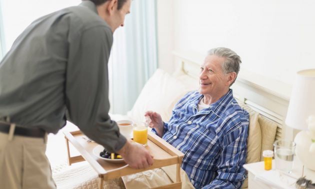 Homme Age d'Or apportant un plateau-repas à une personne âgée